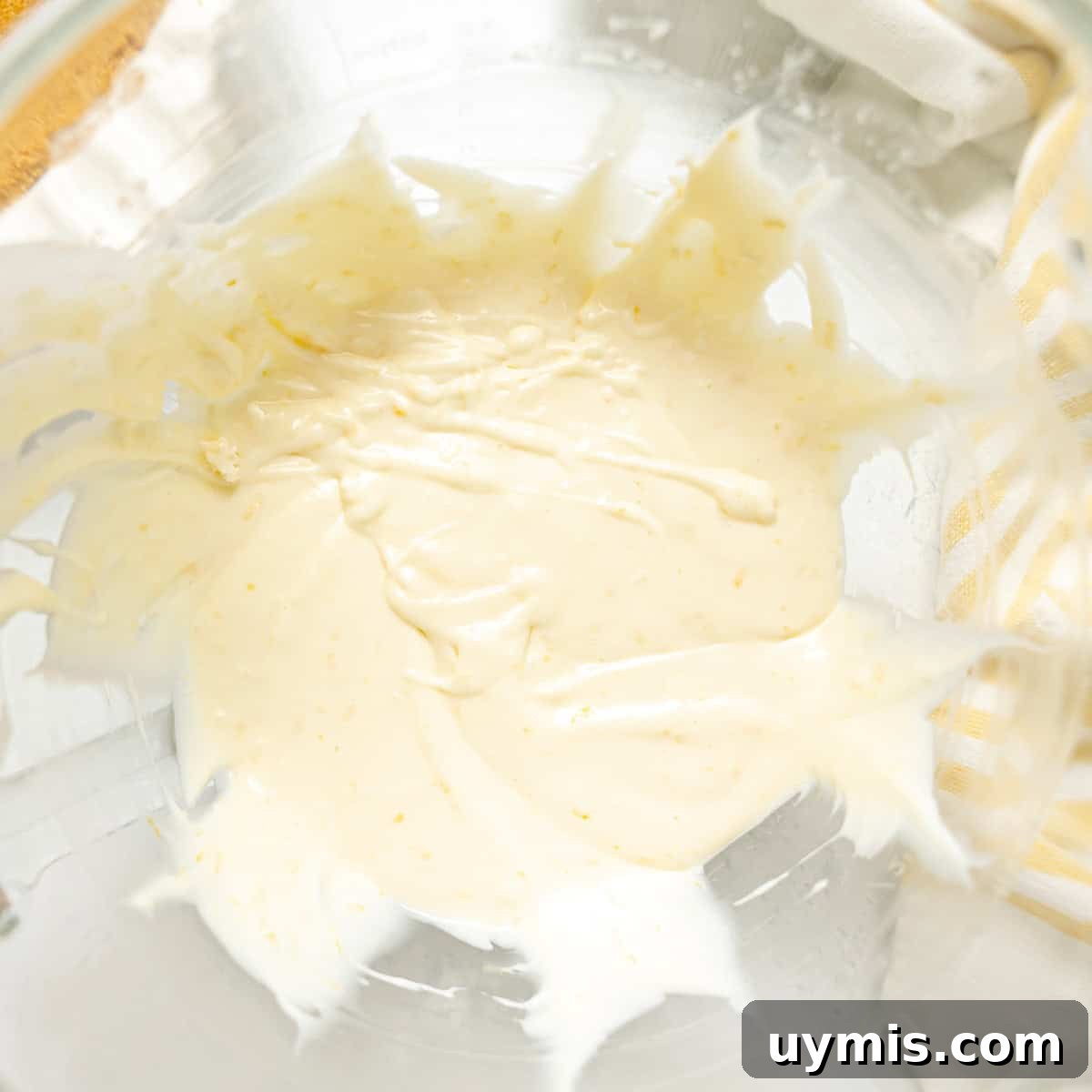 Lemon Icebox Pie Recipe with Creamy No Bake Filling 6 A glass bowl containing a small amount of creamy, pale yellow mixture, partially spread on the sides of the bowl.