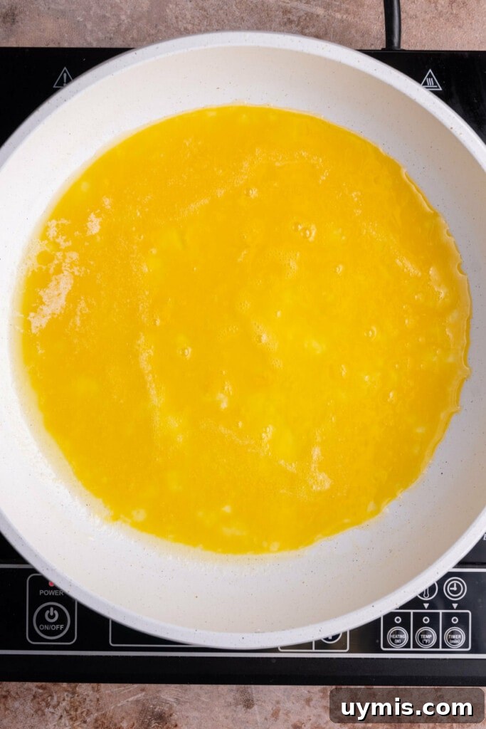 Smoked Salmon Omelet with Lox and Schmear, 5 Ingredients 6 Beaten eggs cooking in a pan of hot butter.