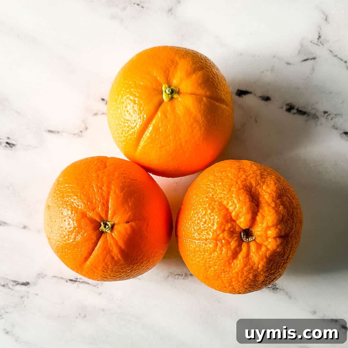 Fresh oranges on a white marble counter.