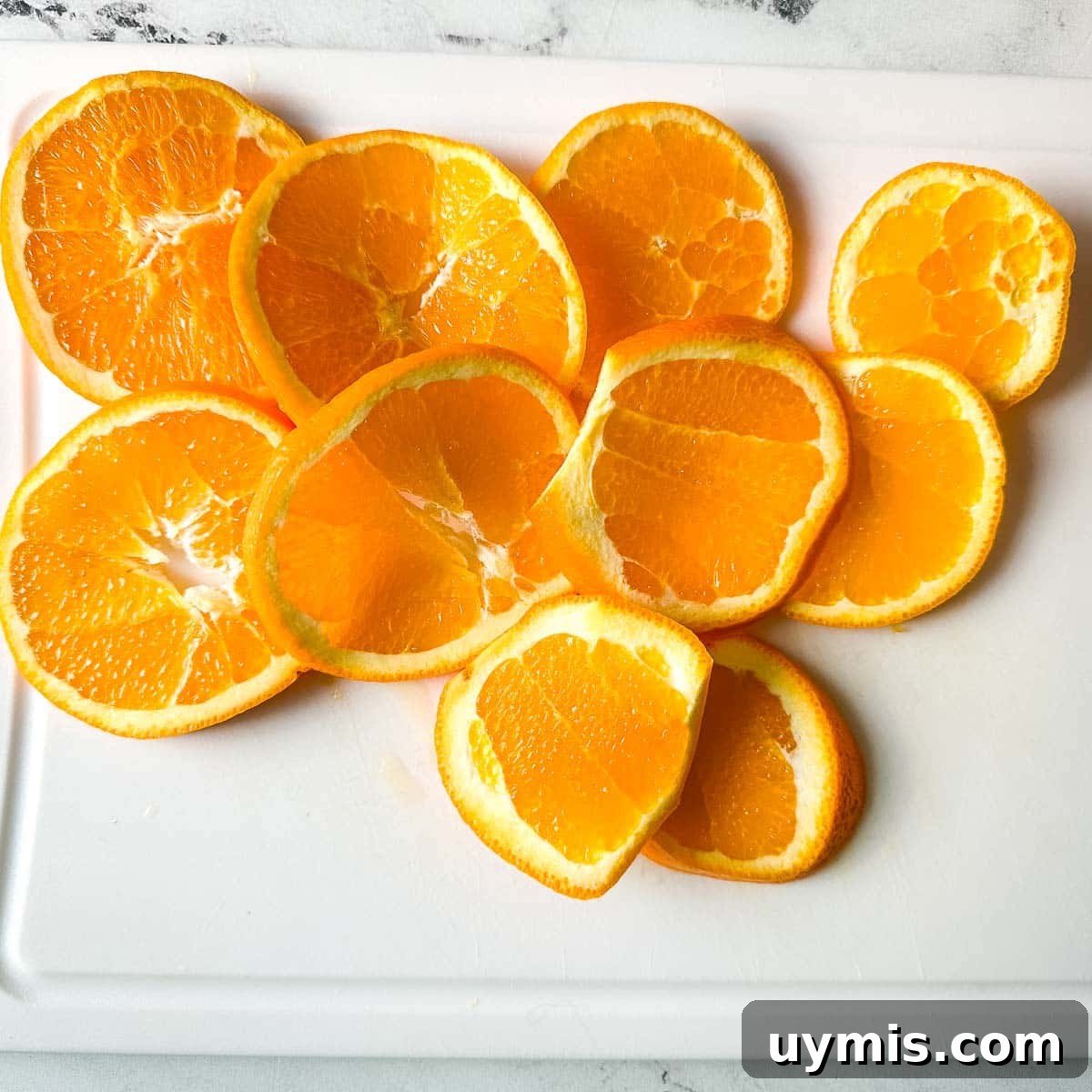 Sliced oranges on a white cutting board.
