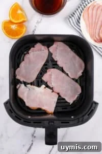 Air Fryer Canadian Bacon Breakfast Slices 13 An air fryer basket with Canadian bacon slices inside.