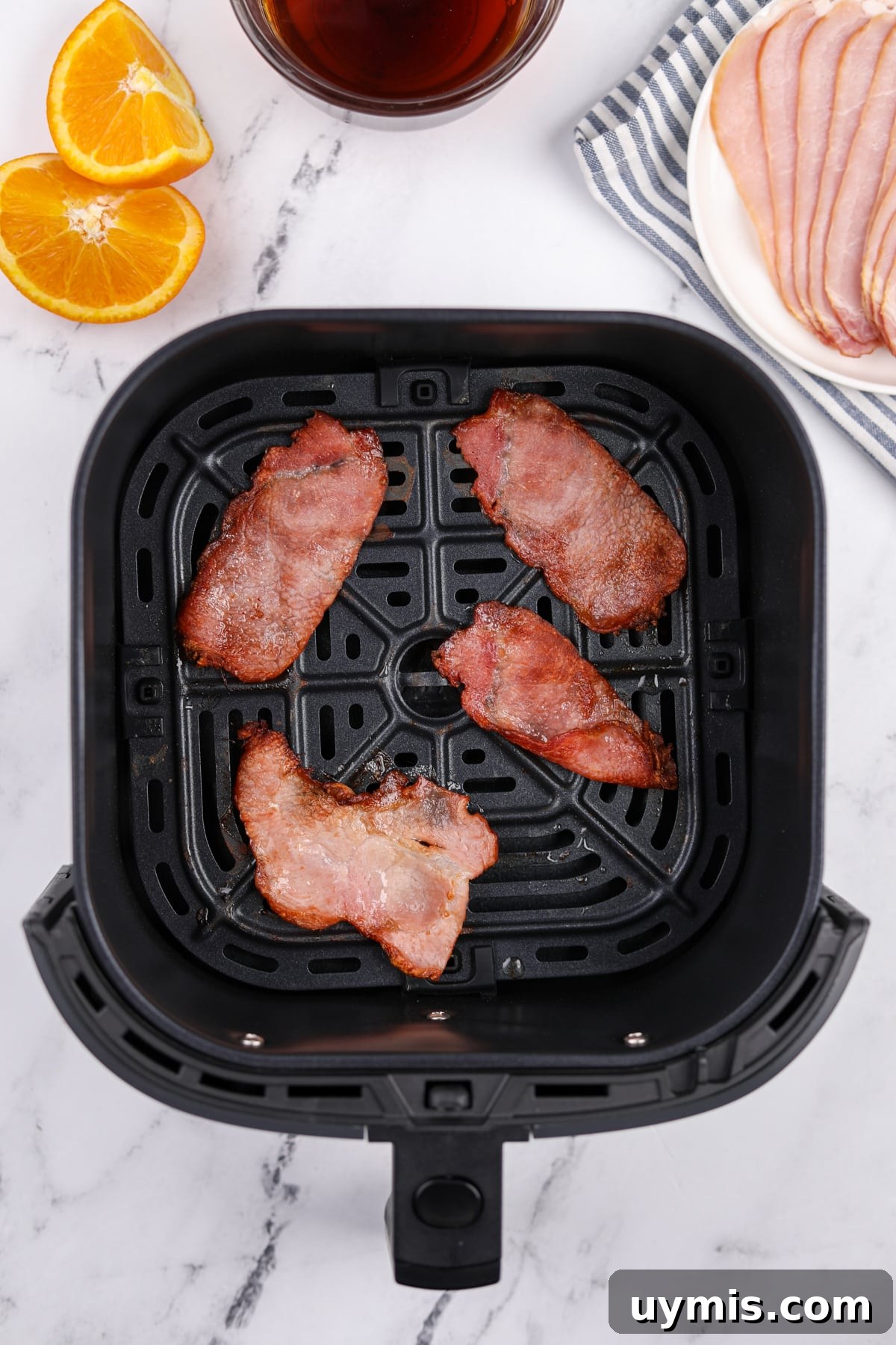 Air Fryer Canadian Bacon Breakfast Slices 5 An air fryer basket with four slices of cooked back bacon inside.