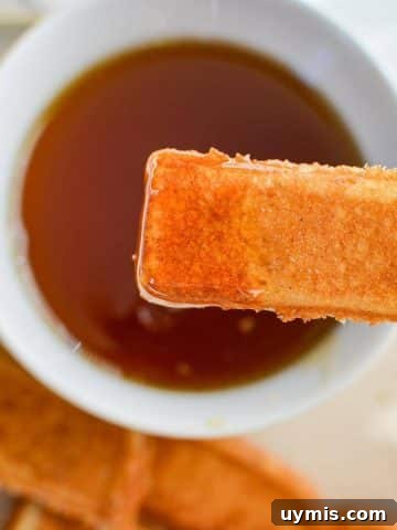 Dipping a French toast stick into a bowl of maple syrup.